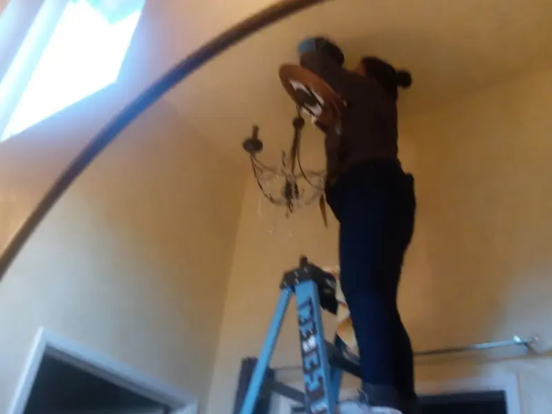 Electrician installing a chandelier in a University City residence